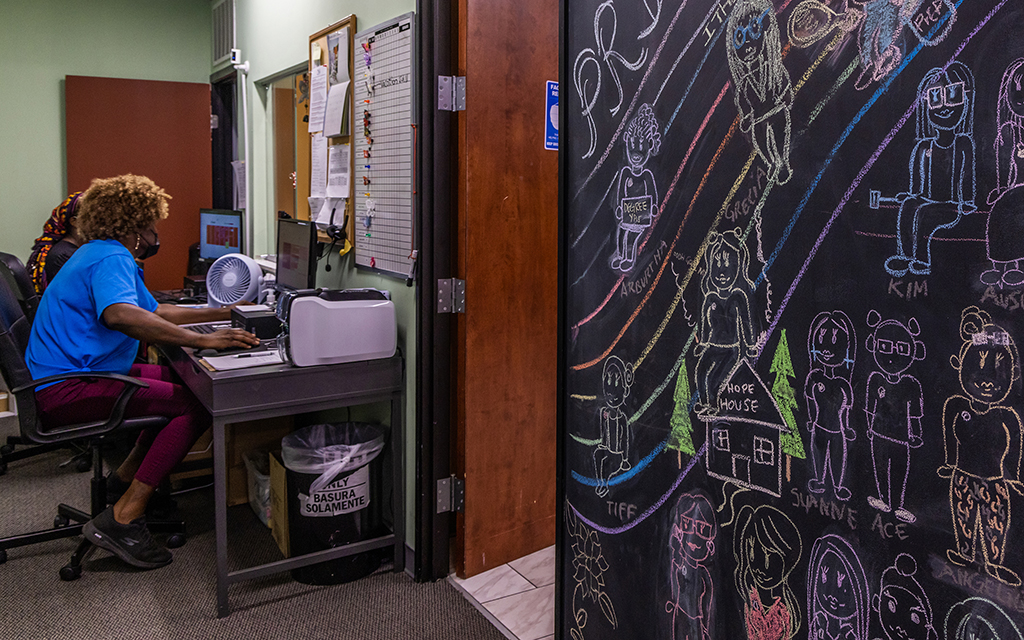 A chalkboard filled with drawings of staff and a large rainbow hangs near the front desk at the TransLatin@ Coalition office in Los Angeles on July 5, 2022. Jimena Sandoval, the group’s communications and marketing coordinator, says it was drawn for Pride Month. (Photo by Jessica Alvarado Gamez/News21)