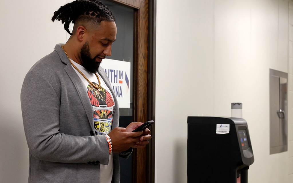 Josh Riddick checks his phone outside the Faith in Indiana office Indianapolis. He fears a new law empowering a statewide review board to establish training standards will mean fewer training hours on such subjects as de-escalation. (Photo by Reagan Creamer/News21)